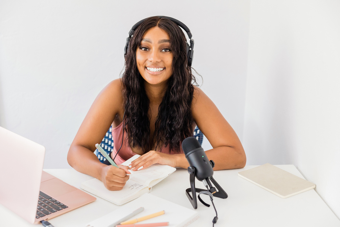 Woman Writing Notes While Recording a Podcast